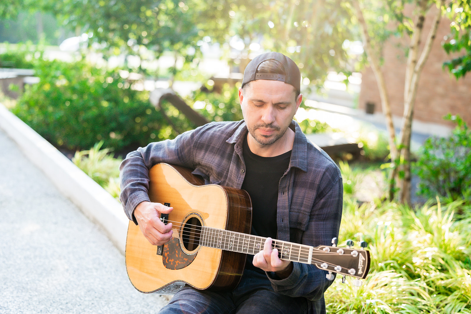Eric Z playing acoustic guitar in a backwards cap